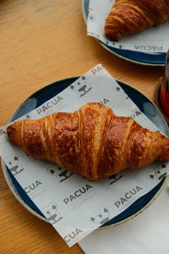 Delicious golden croissant on a blue plate, perfect for a breakfast setting.